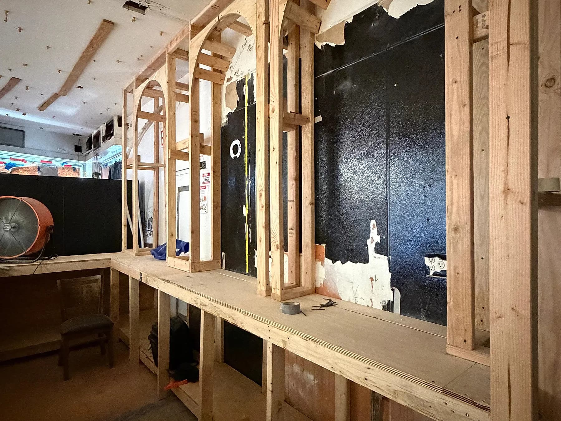 Arched timber millwork framed out along a bar wall before its panelling goes on