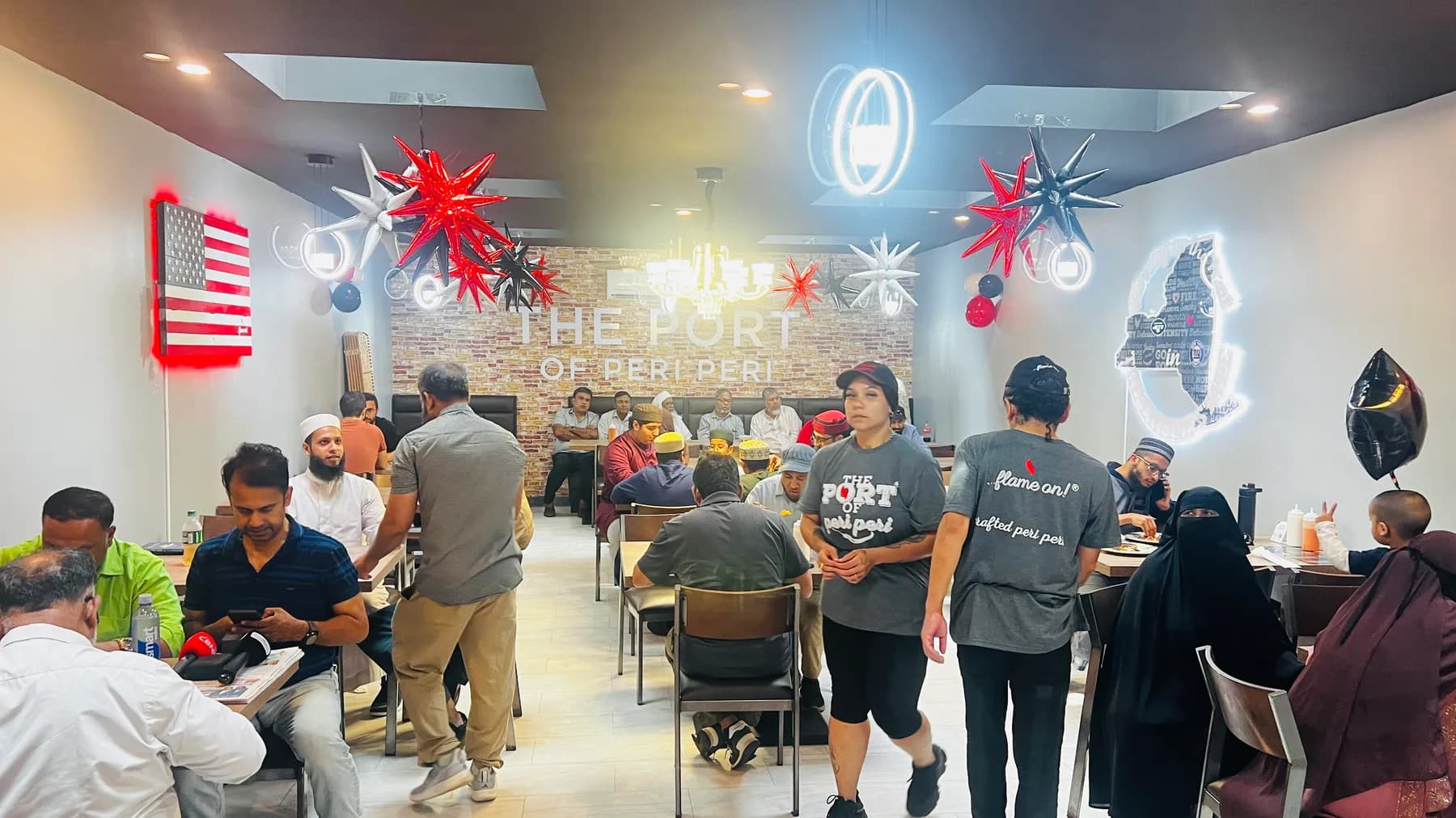 A full dining room at The Port of Peri Peri's grand opening, under starburst pendant lights