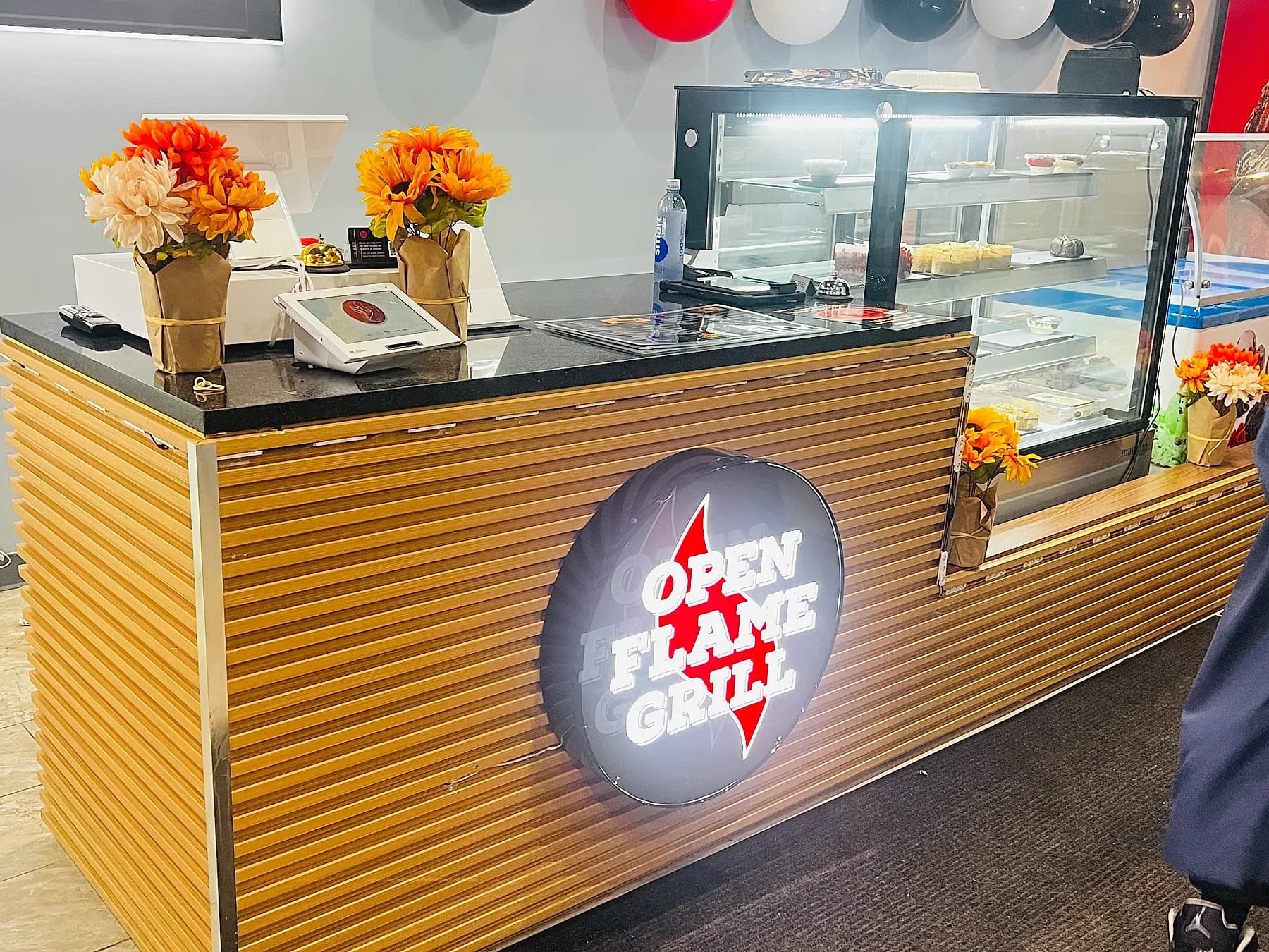 The slatted-wood service counter at The Port of Peri Peri under its Open Flame Grill sign