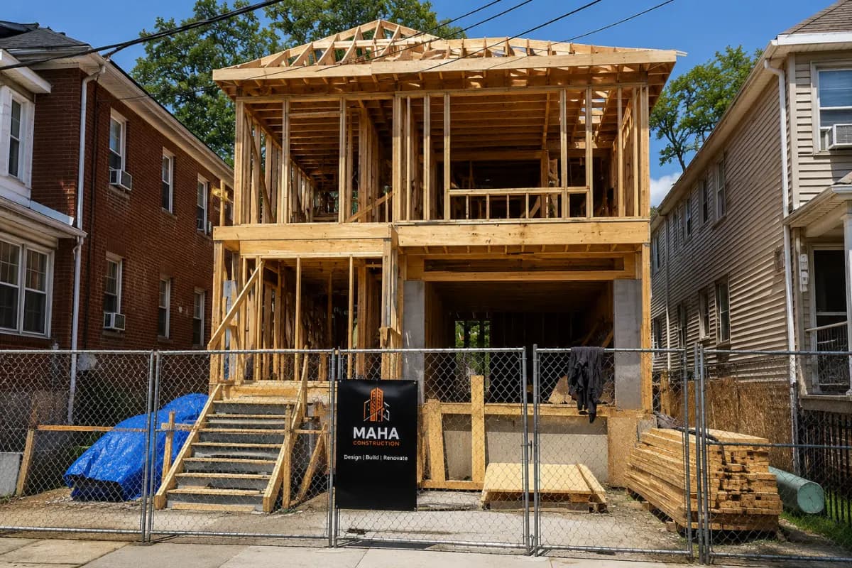 A Maha Construction job site fence in front of a residential home under framing