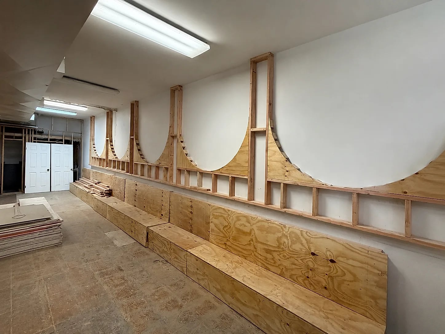 A restaurant interior mid-build, its curved wall panels framed out in bare plywood